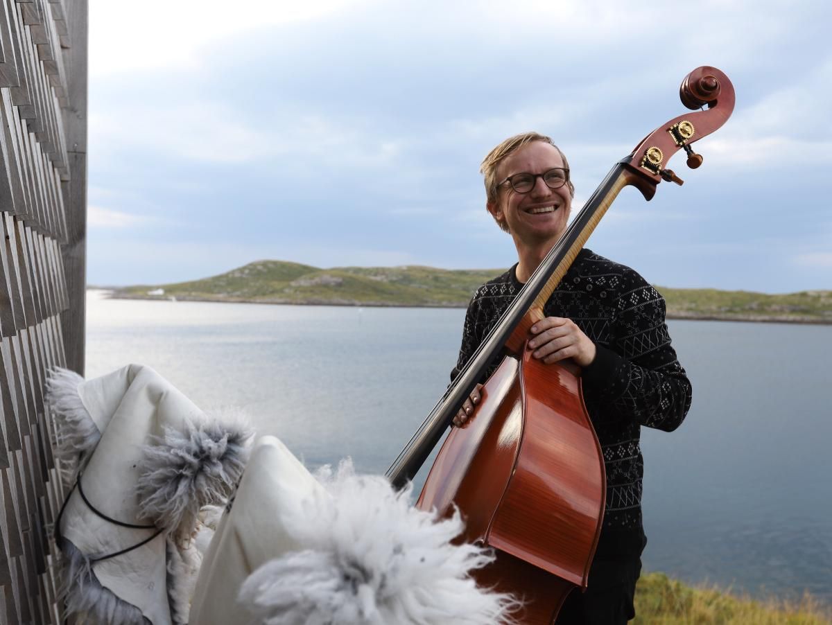 Sigurd Hole står ved sjøen og holder et instrument