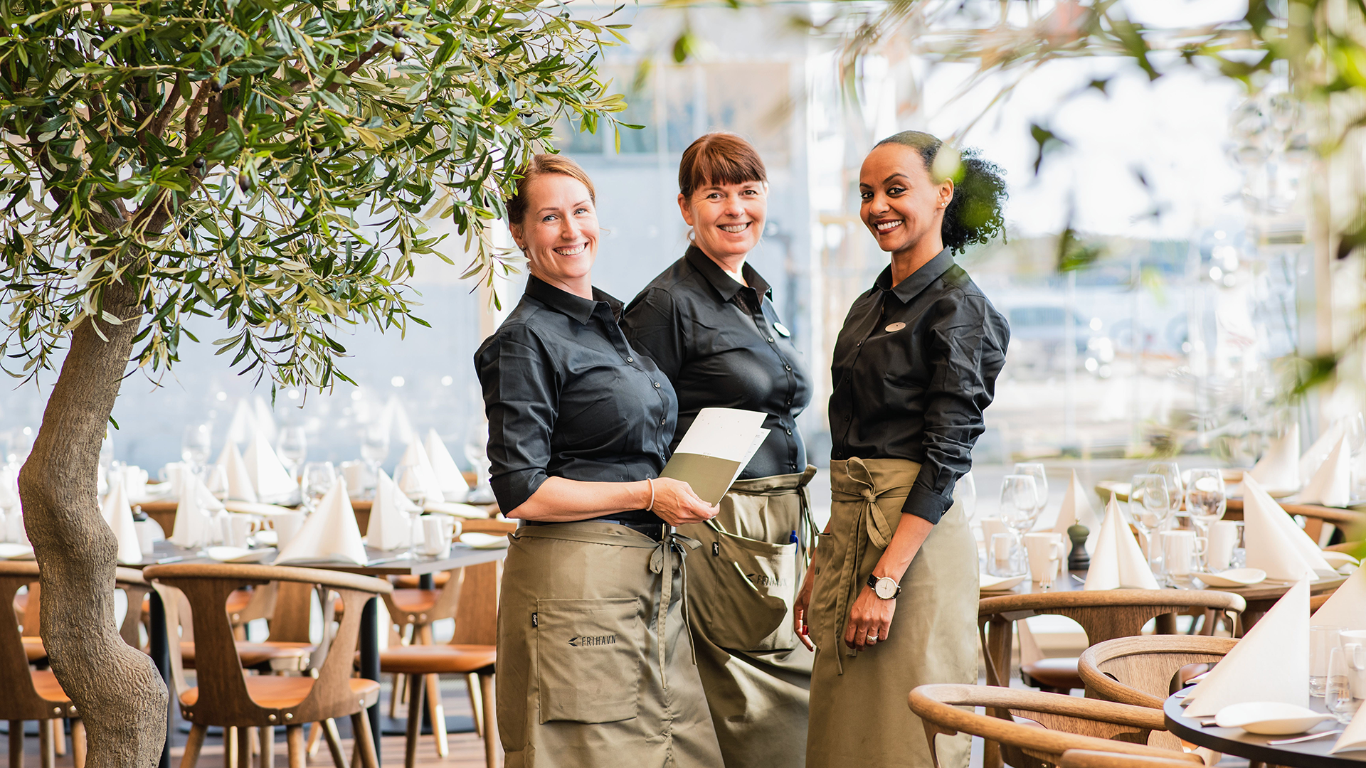 Bilde av tre servitører stående i front av restauranten 