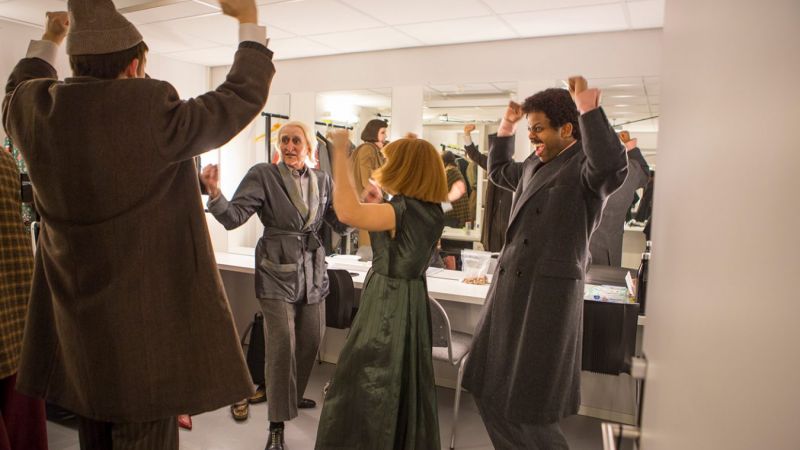 Bilde av jublende skuespillere i kostyme inne i en garderobe.