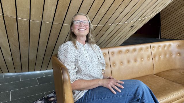 smilende dame som sitter i en sofa i foajeen til kilden teater og konserthus