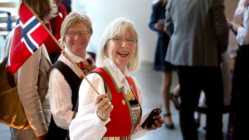 Smilende dame i bunad med norsk flagg