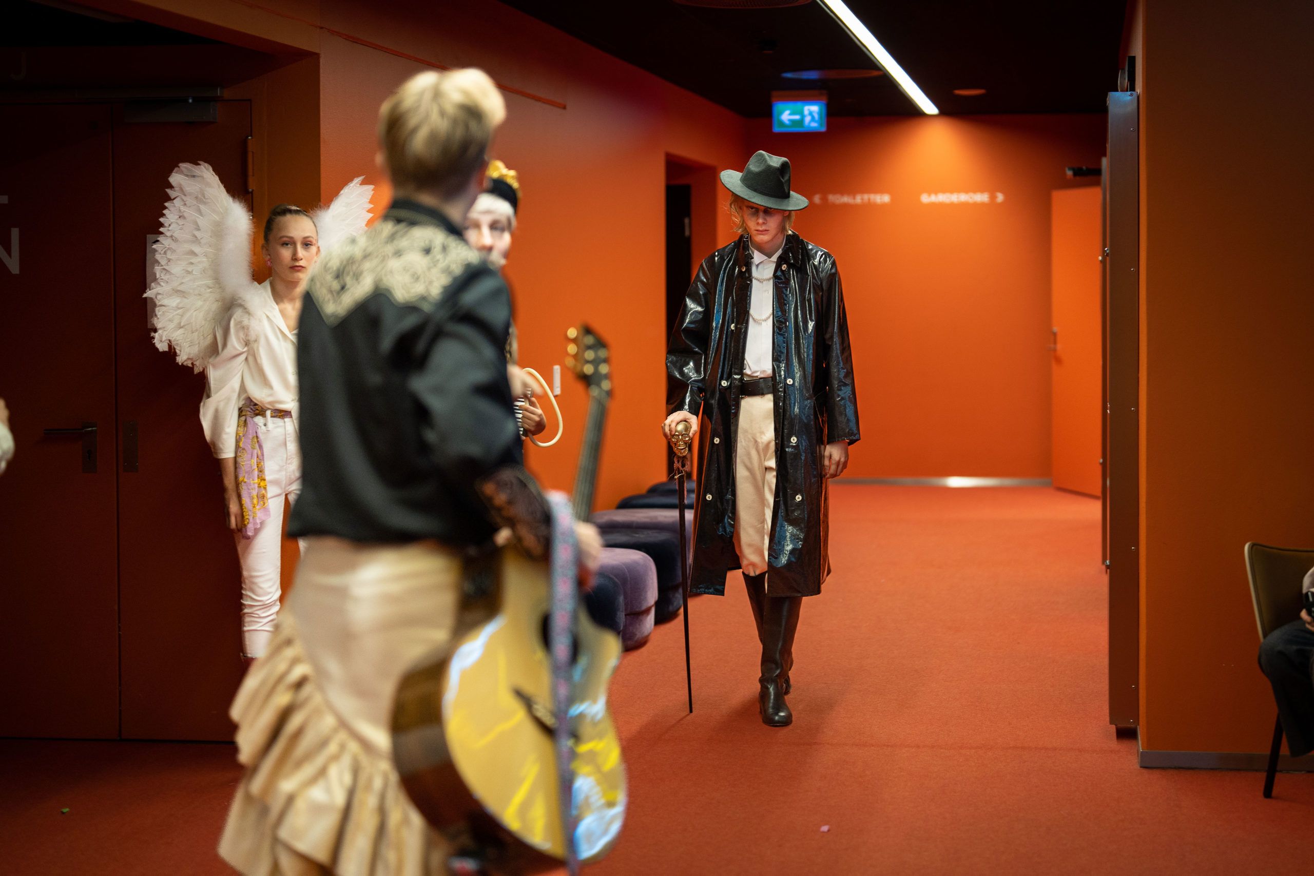 Sint mann går mot mann med gitar i et orange rom.