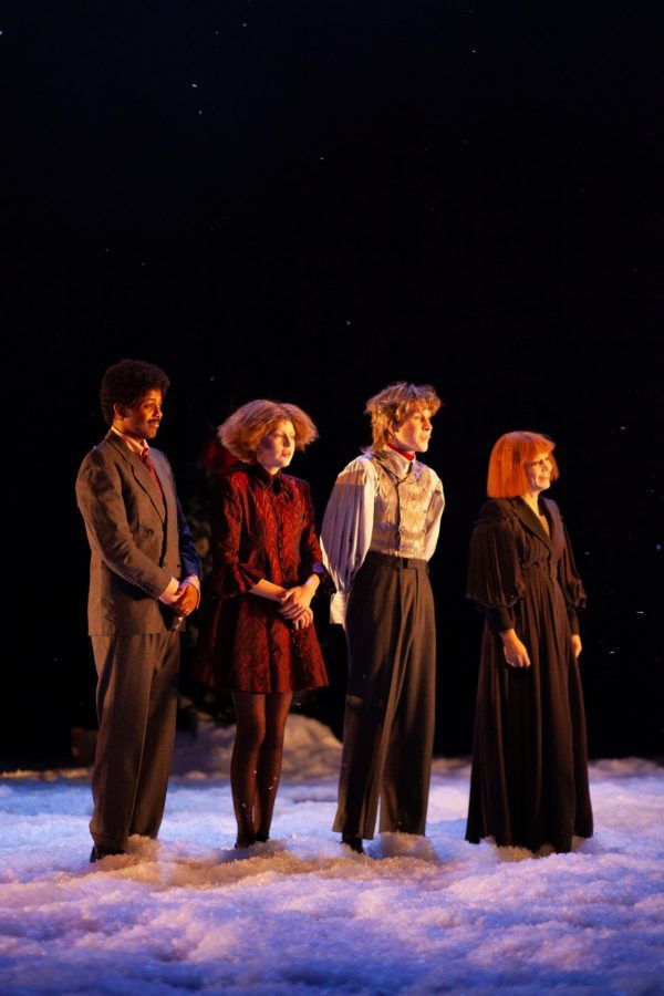 Fire skuespillere fra forestillingen En julefortelling som står samlet på en scene med kunstig snø rundt.