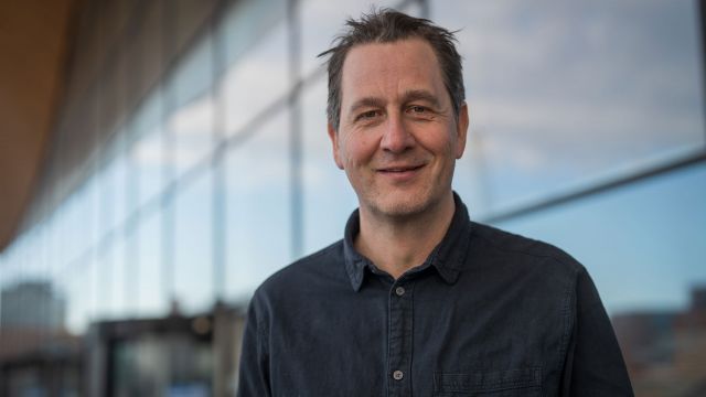 Portrettbilde av Henrik Rafaelsen foran Kildens bølgevegg.