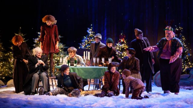 Mange mennesker rundt et juledekket bord. Alle er glade