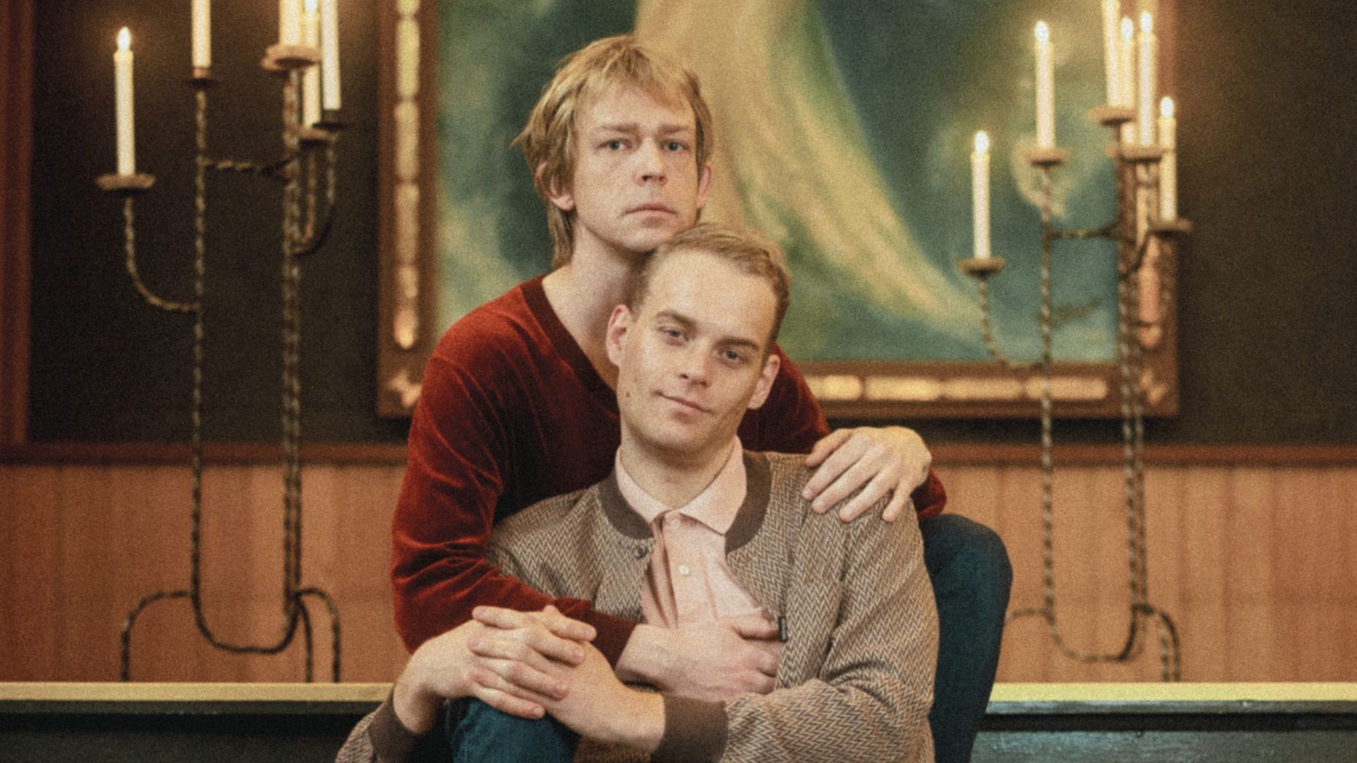 Bilde hovedpersonene i teaterforestillingen Villskudd. To homofile menn, sittende på trappen til et kristent alter.  