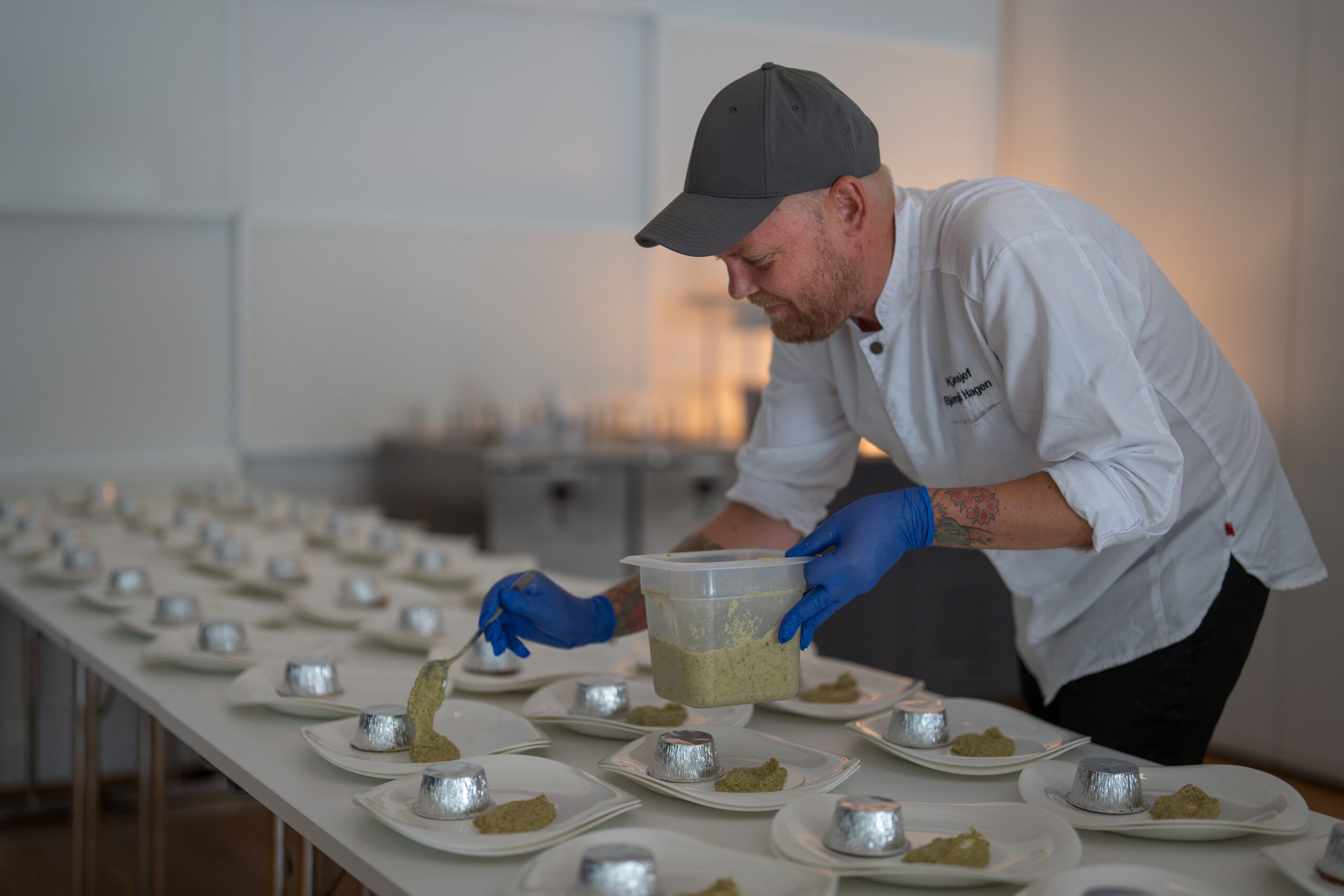 Kjøkkensjef Bjørn Egil lener seg over et bord og gjør klar mat til et arrangement