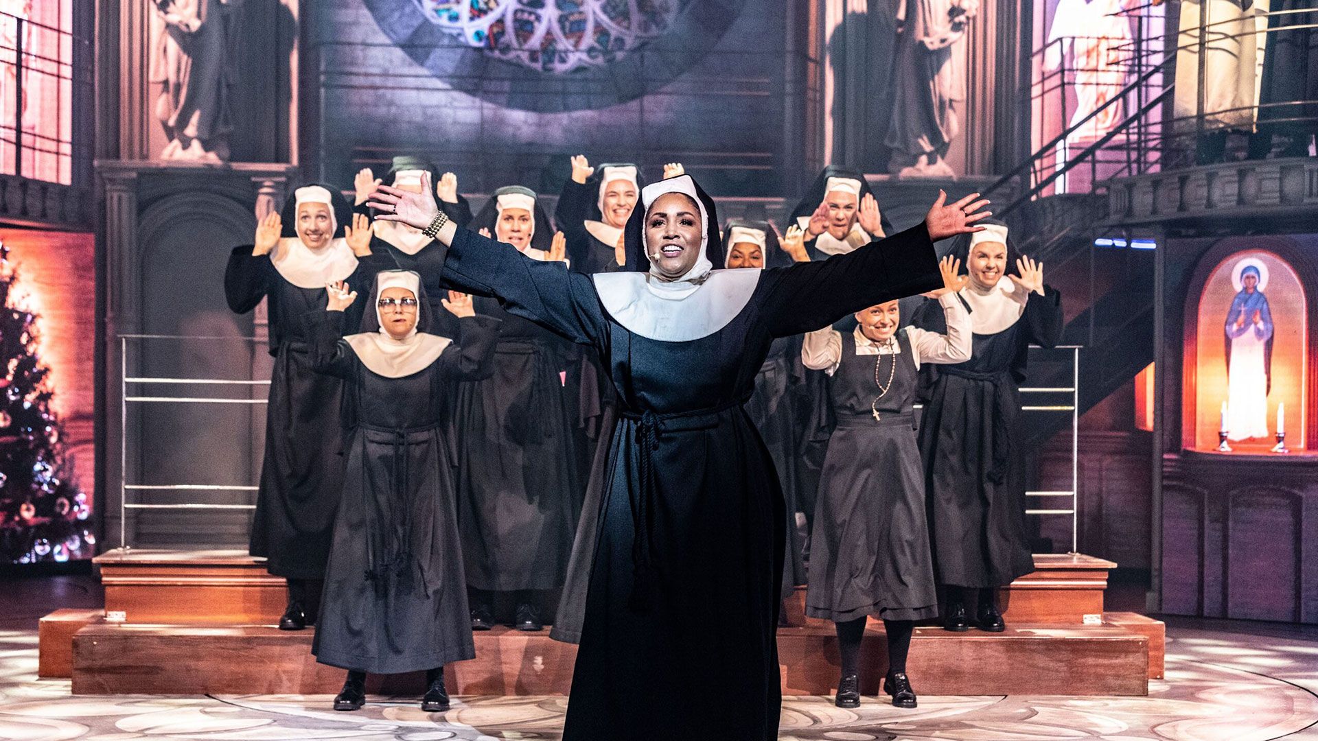 Forestillingsbilde fra Sister Act. Damer i nonne-kostyme danser på scenen.