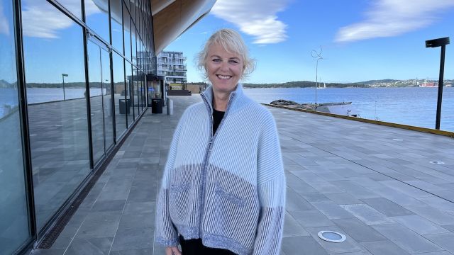 Tidligere teatersjef i Kilden Ingrid Forthun står smilende foran Kilden teater og konserthus