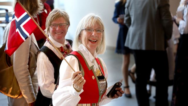 Smilende dame i bunad med norsk flagg