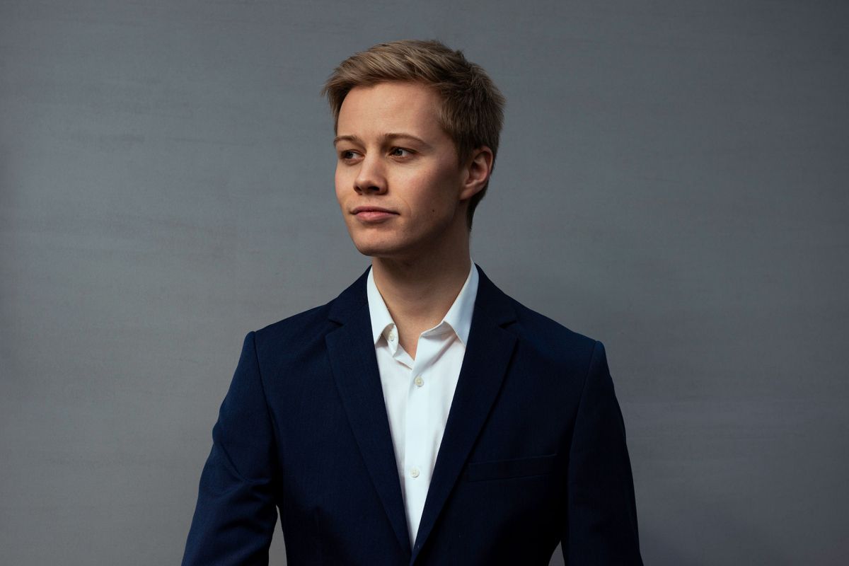 Privat portrettbilde av Magnus Fremstad, blond mann i mørk blå dress foran grå vegg.