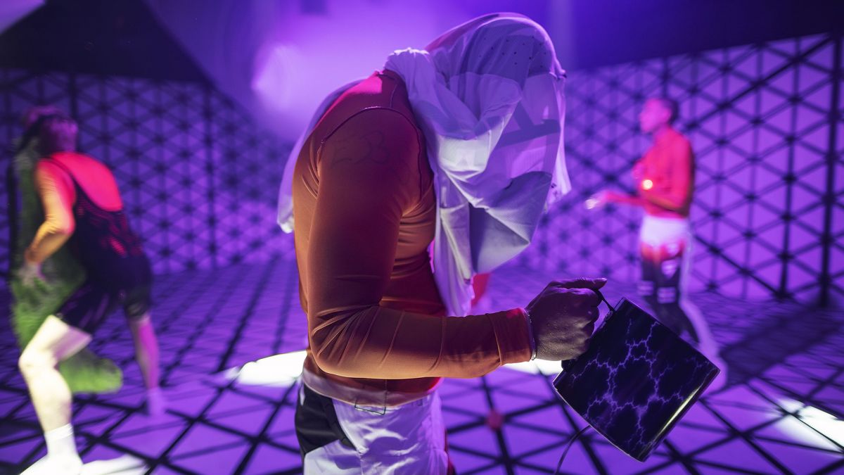 Gutt med hette og veske i rutete svart-hvitt scenografi.