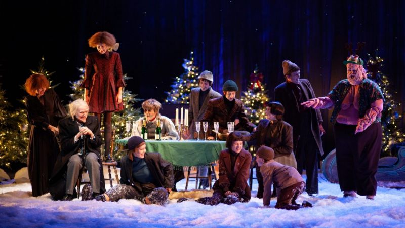 Mange mennesker rundt et juledekket bord. Alle er glade