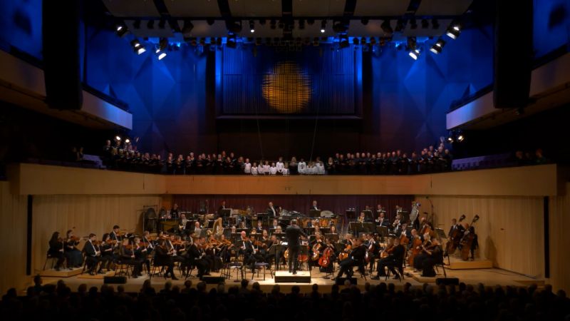 Bilde av et symfoniorkester og kor på en scene.