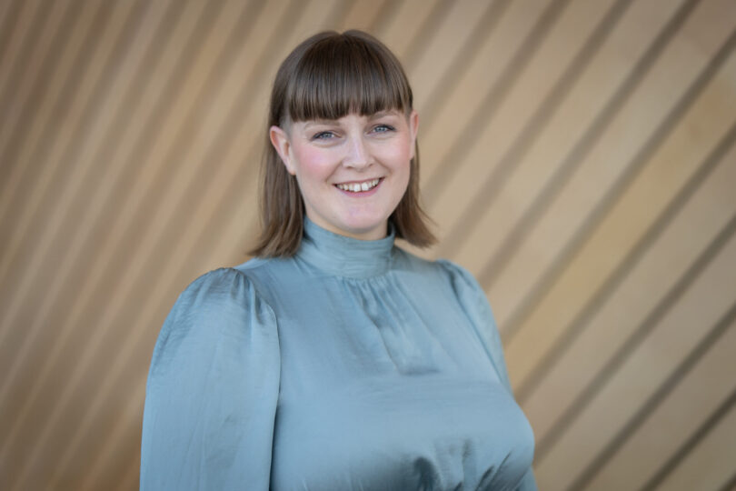Portrettbilde av en smilende kvinne i blå bluse.