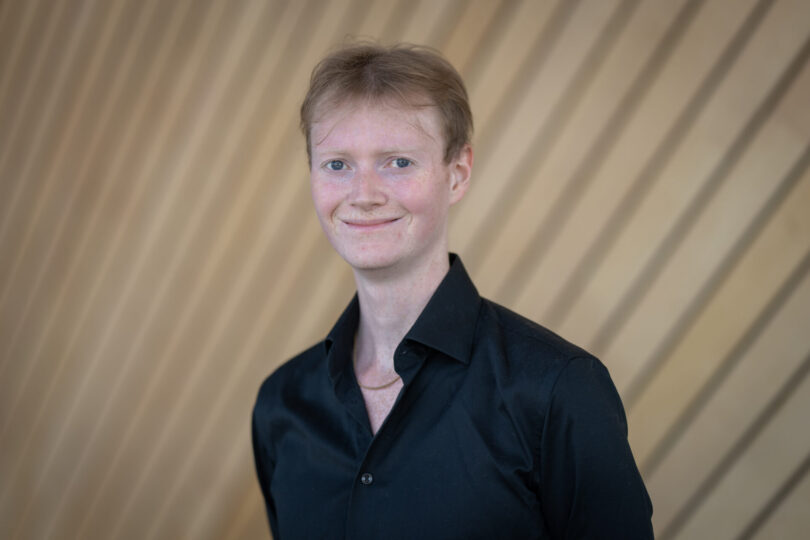 Portrettbilde av en smilende mann i mørk blå skjorte.