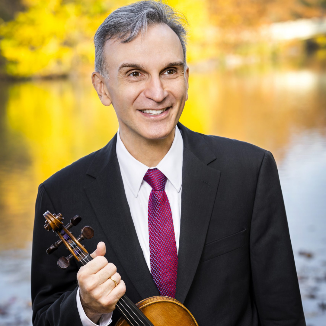 mann som smiler foran en innsjø med fiolin