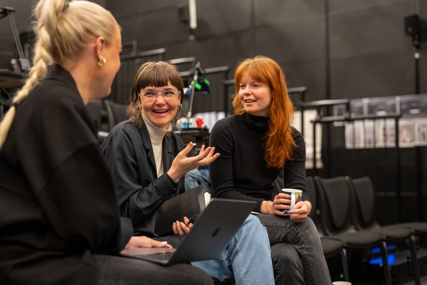 Tre kvinner sitter på stol.