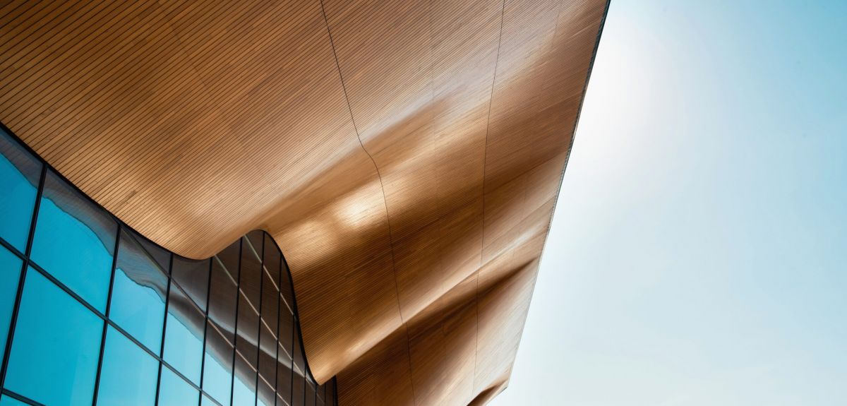 Kilden-byggets fasade med bølgete tak og vo stor vindusfasade mot blå himmel