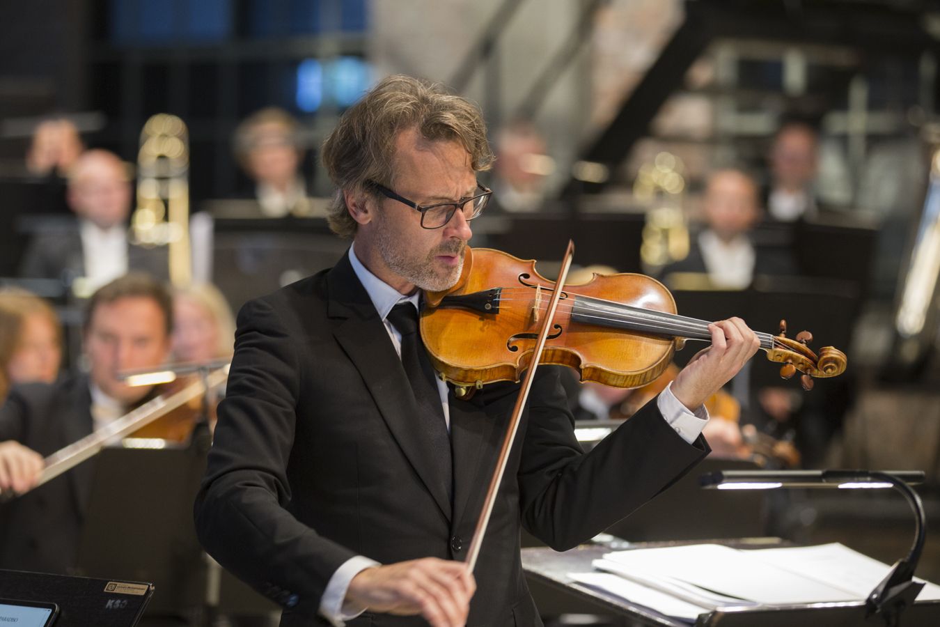 Mann i mørk dress som spiller fiolin.