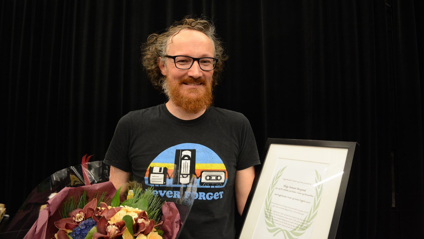 Mann med skjegg og briller som holder blomsterbukett og innrammet dokument.