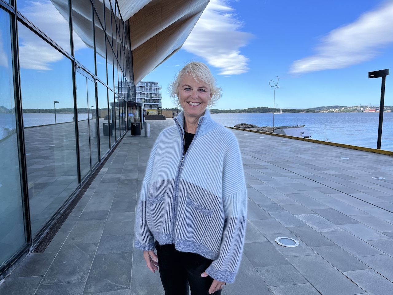 Tidligere teatersjef i Kilden Ingrid Forthun står smilende foran Kilden teater og konserthus