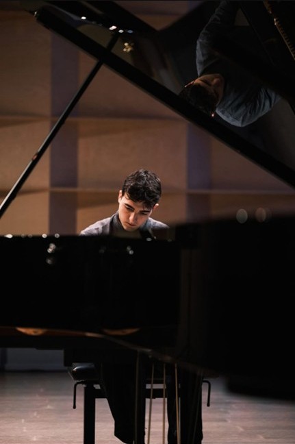 A close-up of a piano with a pianist sitting and playing