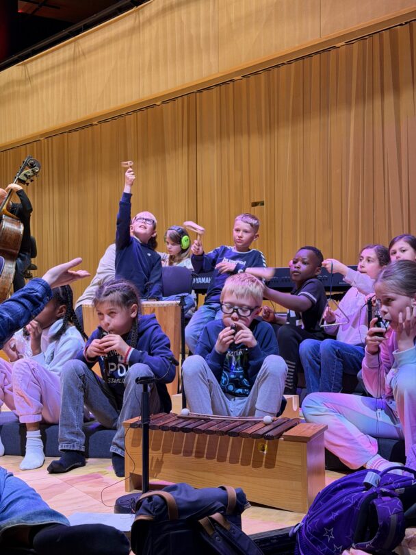 Elever fra 3. klasse spiller sammen med Kristiansand symfoniorkester på scenen i konsertsalen i Kilden