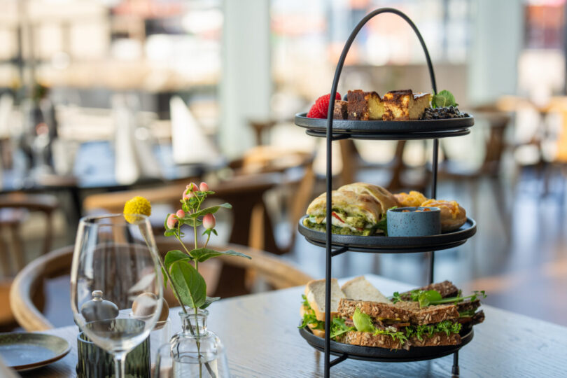 A three-tiered tray, with each tier featuring items such as croissants, sandwiches, and pastries